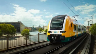 Moderner Regionalzug der ODEG fährt über eine Brücke in Berlin mit Blick auf die Spree und Stadtgebäude