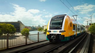 Moderner Regionalzug der ODEG fährt über eine Brücke in Berlin mit Blick auf die Spree und Stadtgebäude