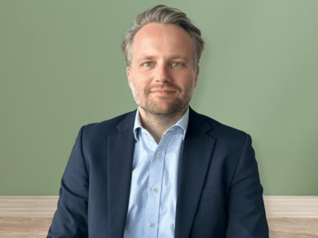 Robert von der Heide, Referent Unternehmenskommunikation bei NETINERA Deutschland GmbH, in einem professionellen Business-Porträt vor grünem Hintergrund, mit dunkelblauem Sakko und hellblauem Hemd.