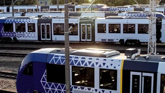 Mehrere moderne vlexx-Züge stehen auf Gleisen in einem Rangierbahnhof bei Tageslicht, umgeben von Oberleitungen und Technik
