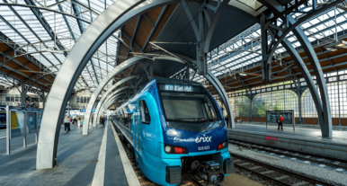 Moderner blauer Regionalzug der Marke erixx Holstein steht im überdachten Bahnhof mit markanter Stahl- und Glasarchitektur.