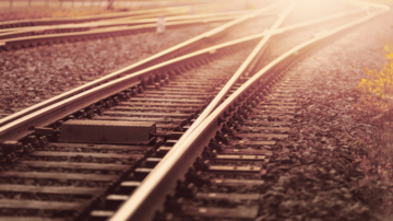 Nahaufnahme von Eisenbahnschienen mit Weichen im warmen Sonnenlicht, symbolisch für Mobilität, Infrastruktur und Schienenverkehr.