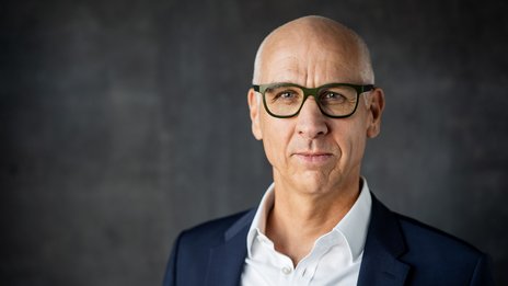 Markus Resch, CEO der NETINERA Deutschland GmbH, in einem professionellen Business-Porträt mit dunkelblauem Anzug und weißem Hemd vor modernem, grauem Hintergrund.