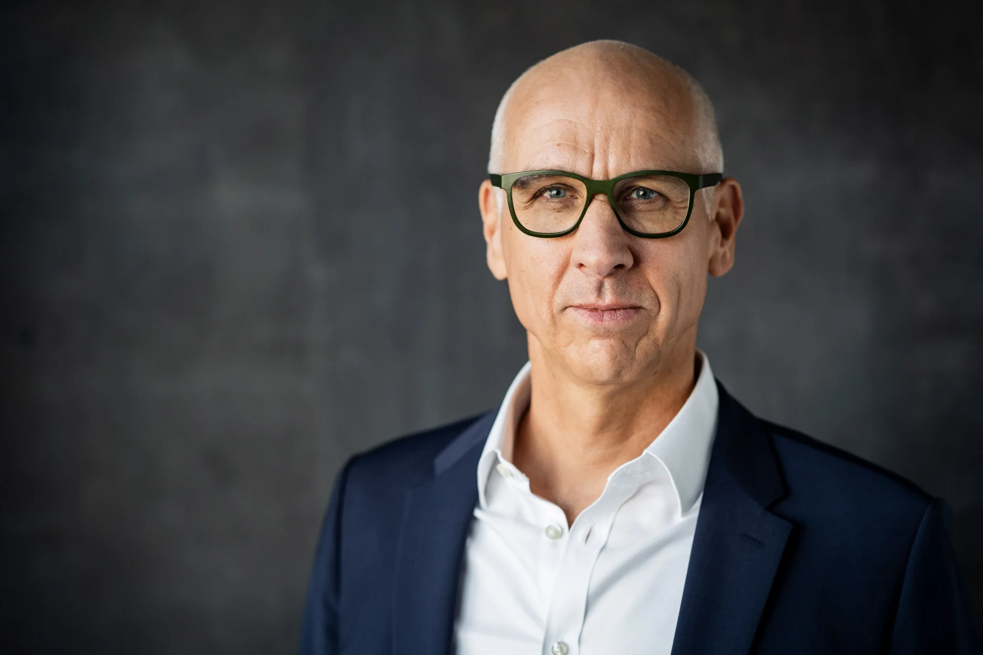 Markus Resch, CEO der NETINERA Deutschland GmbH, in einem professionellen Business-Porträt mit dunkelblauem Anzug und weißem Hemd vor modernem, grauem Hintergrund.