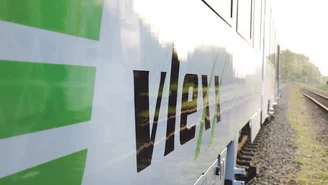 Nahaufnahme eines modernen Zuges mit vlexx-Logo auf der Außenseite, aufgenommen entlang der Gleise bei Tageslicht