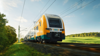 Moderner Elektrozug fährt auf sonniger Strecke durch grüne Landschaft mit Bäumen und Wiesen