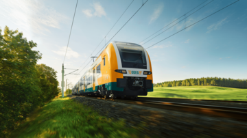 Moderner Elektrozug fährt auf sonniger Strecke durch grüne Landschaft mit Bäumen und Wiesen