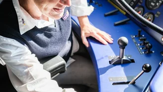 Lokführerin steuert einen modernen Zug vom Führerstand aus, mit blauer Bedienkonsole, Hebeln und Instrumenten für die Zugsteuerung.