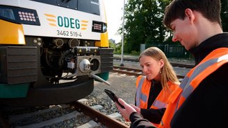 Zwei Personen in Warnwesten führen Sicherheitskontrolle an einem ODEG-Zug auf Gleisen durch und nutzen ein mobiles Gerät